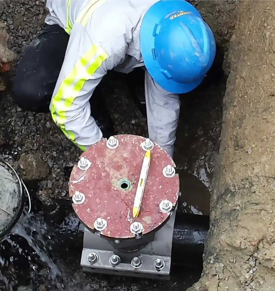 lineman working on a valve insertion installation on an underground water supply pipe for a municipality.