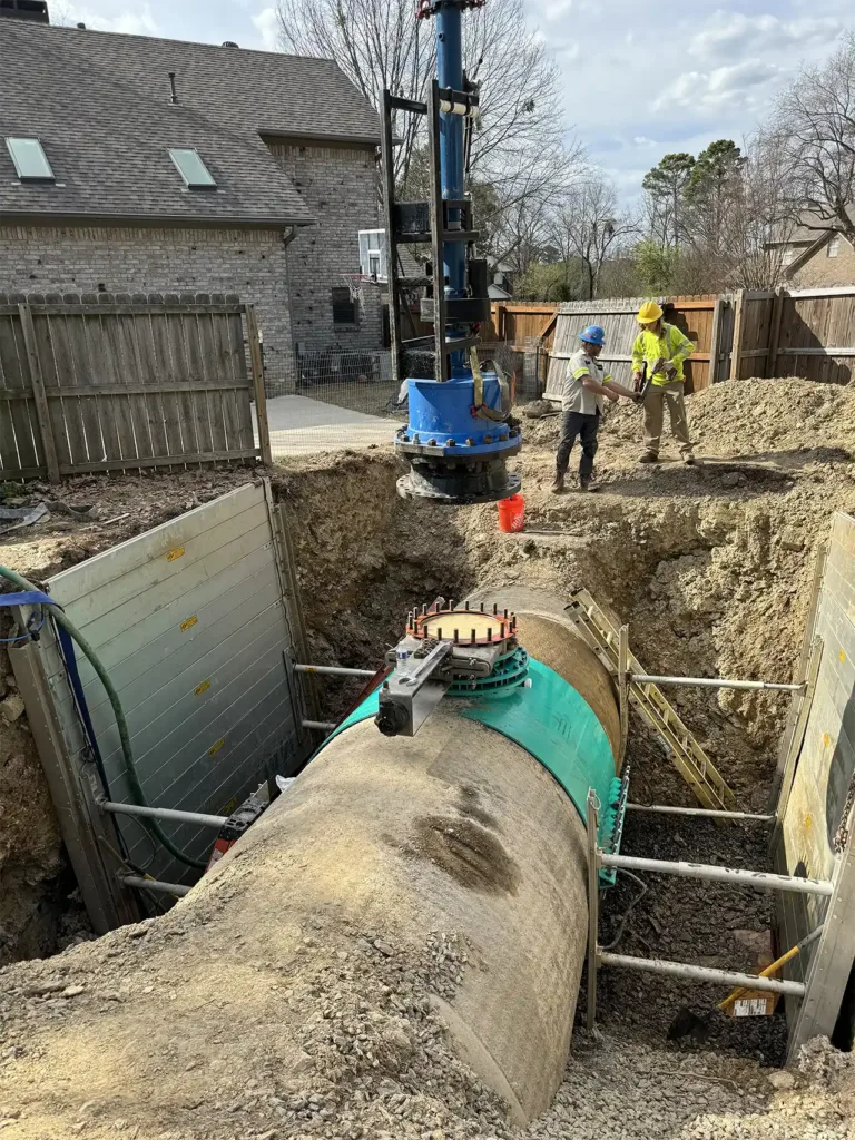 men standing next to a large section of PCCP pipeline during repair work.